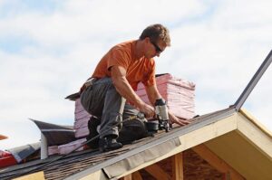 Homeowner inspecting roof shingles and gutters from a ladder beside a suburban house